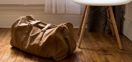 A travel bag stands on the floor next to a chair