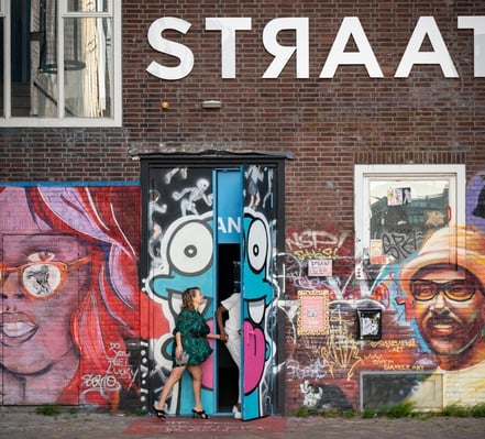 Art'otel London Hoxton Markenmotiv mit Wandkunst und zwei Gästen, die durch eine Hintertür eintreten