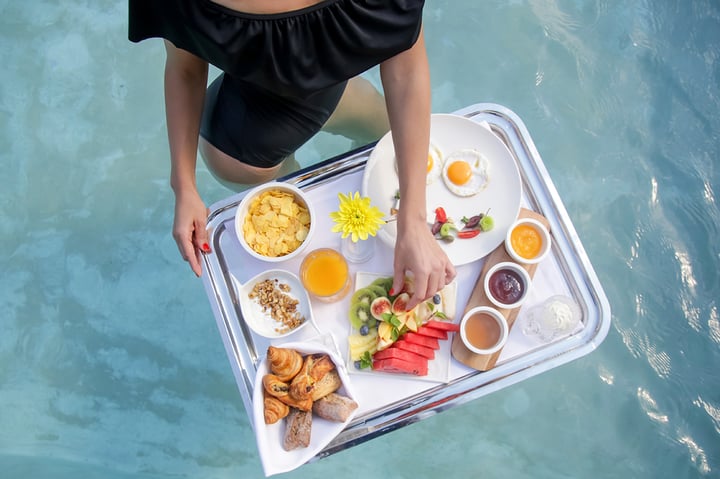 Avaton Hotels image with a model eating from a floating breakfast tray in a hotel pool