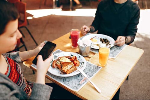 Two people having dinner on a square wooden table