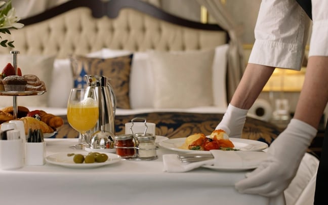 Image of a luxury hotel room with the room service tray's being delivered by a staff member