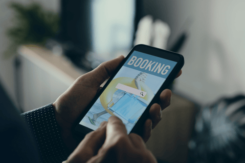 a guest or a customers holding a mobile phone with a hotel booking interface on the screen