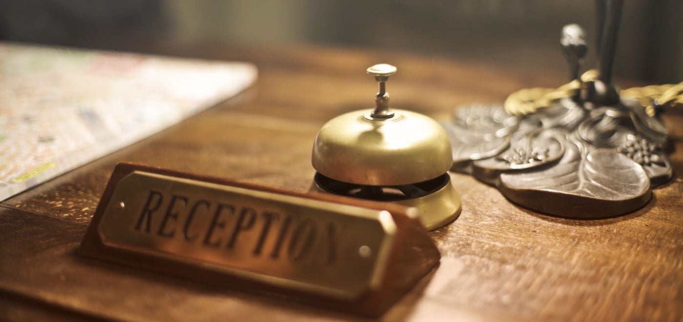 a hotel reception front desk with a sign and a service bell