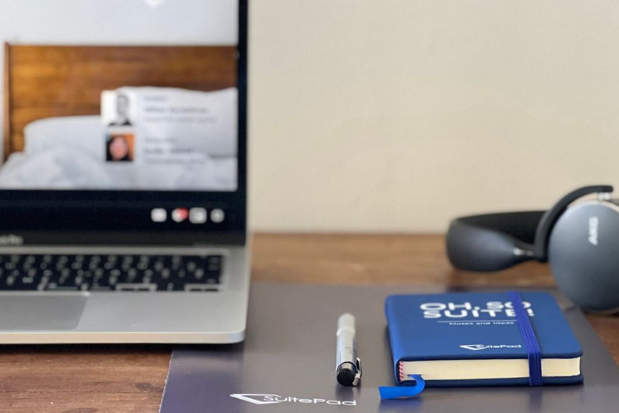 A laptop, a notebook and headphones on a desk 