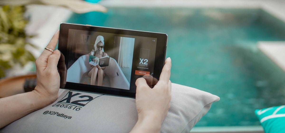 SuitePad Cross Hotels Pressemitteilung-Headerbild mit dem Tablet im Zimmer, das von einem Gast mit der Hotelinstallation genutzt wird 