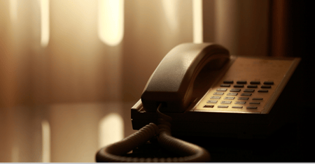 sepia image of an outdated hotel phone on a hotel room table