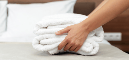 a housekeeping staff putting towels on a hotel bed