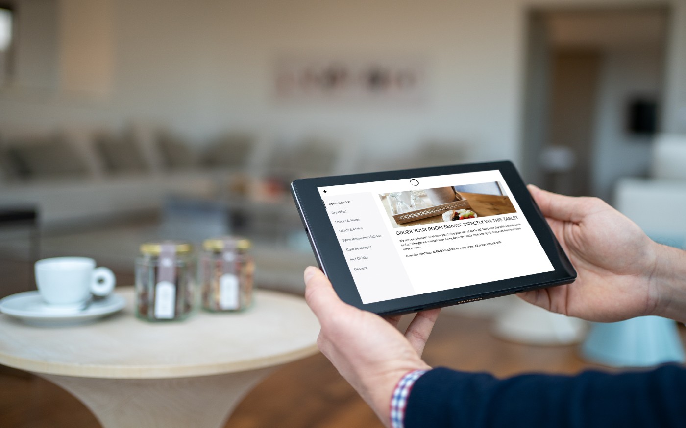 Hands holding SuitePad device in a hotel room