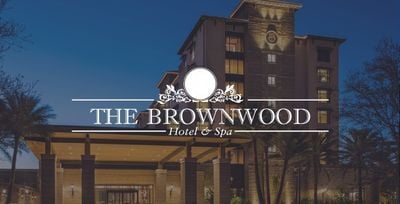 The Brownwood Hotel and Spa logo on a hotel exterior image with a grey overlay