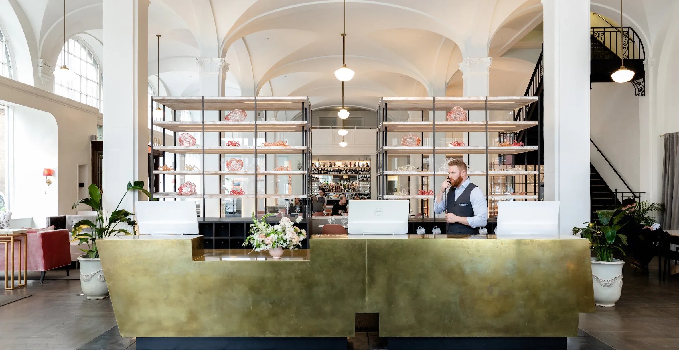 Reception desk in the restored 1916 lobby at Quirk Hotel Richmond, with the hotel restaurant behind